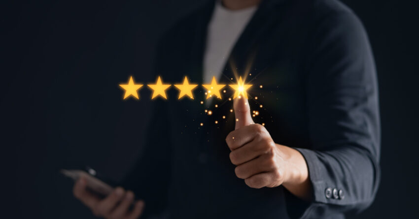 A satisfied customer gives a thumbs up for a five-star rating on his mobile phone, showing his positive feedback.