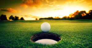 Golf ball about to fall into the cup at sunset