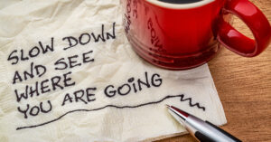 slow down and see where you are going - motivational reminder - handwriting on a napkin with a cup of coffee