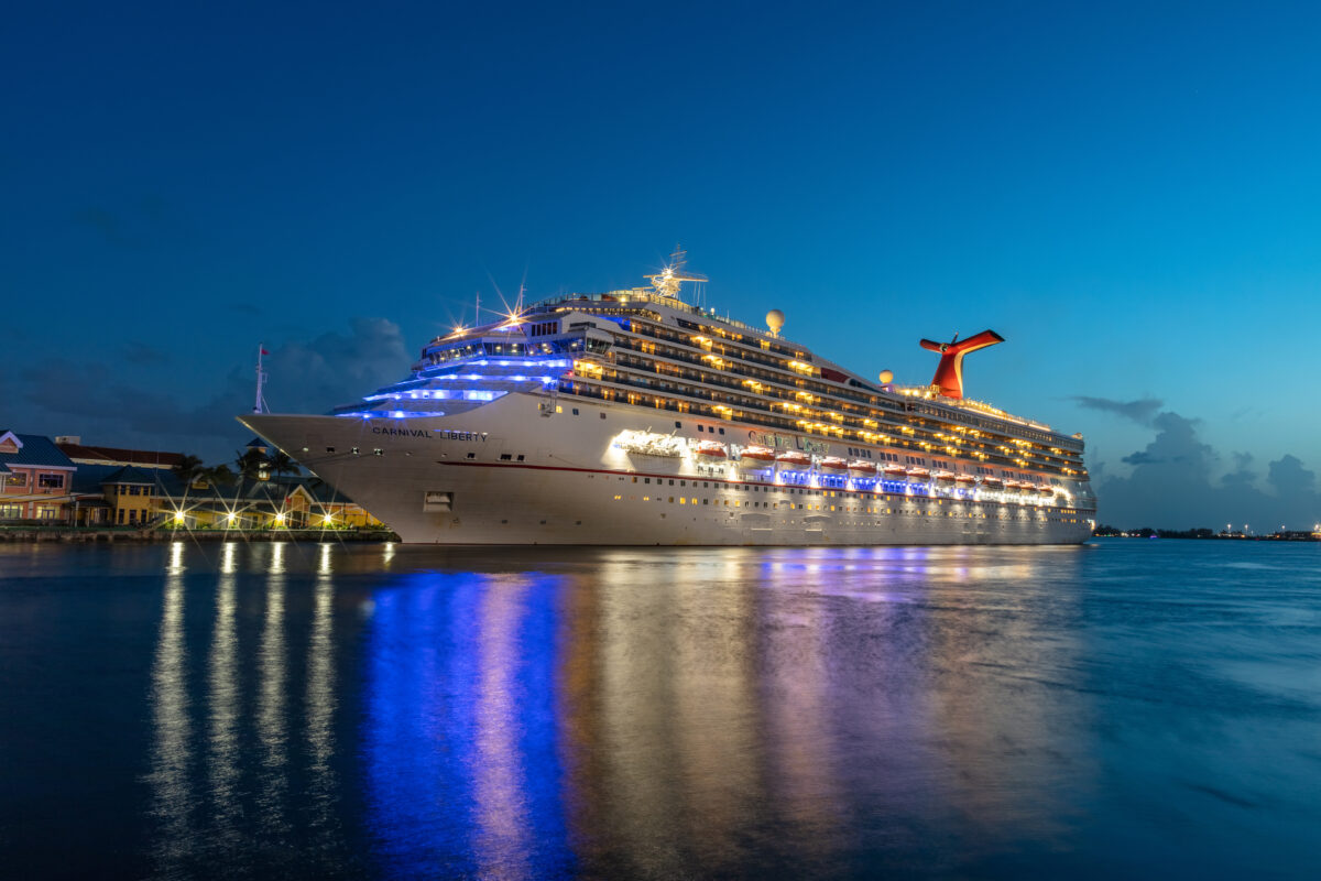 Nassau, Bahamas - July 13, 2019: Carnival Liberty cruise ship docked in Prince George Wharf. Blue hour. Gorgeous reflections of the ship's and port's lights in the harbour water in the foreground.