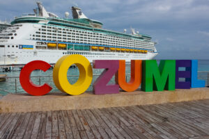 Cozumel, Mexico - May 04, 2022: Royal Carribean cruise ships docked in the Cozumel port during one of the Western Caribbean cruises at Cozumel, Mexico on May 04, 2022. Welcome sign in front of cruise ship.