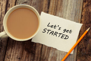 Let's get started inscription on white blank papper. Cup of coffee and pencil, over rustic wooden