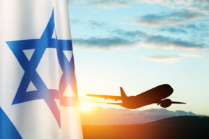 Israel flag and airplane taking off at the sunset sky. Silhouette of an airplane in the sky next to the Israeli flag.